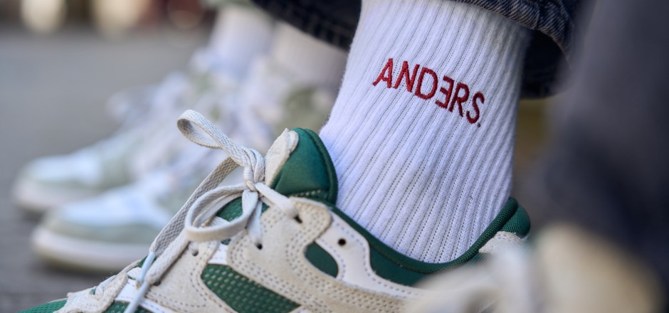 Turnschuh mit weißer Socke in rot bestickt mit dem Schriftzug "Anders"