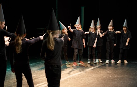 Schülerinnen und Schüler auf der Bühne mit Hut und Zauberstab