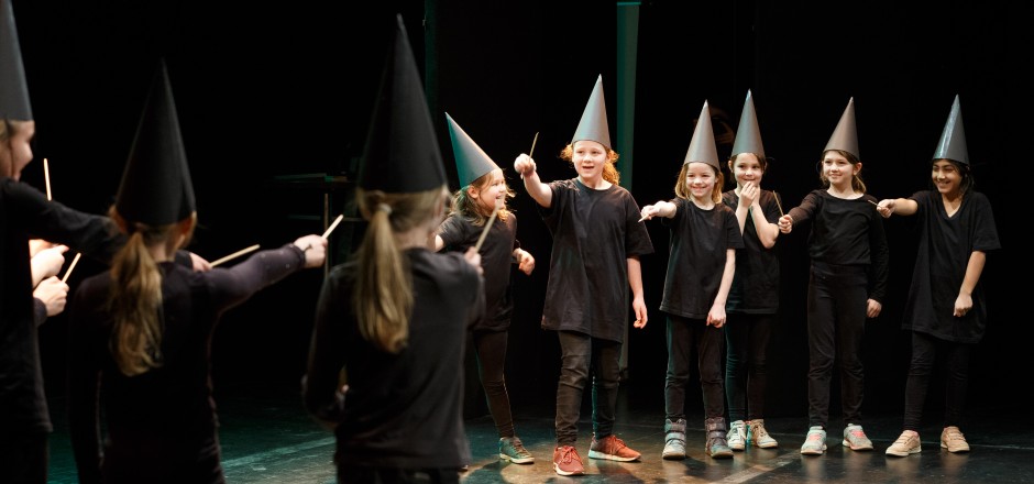 Bild zeigt Schülerin und Schüler auf der Bühne mit Hut und Zauberstab