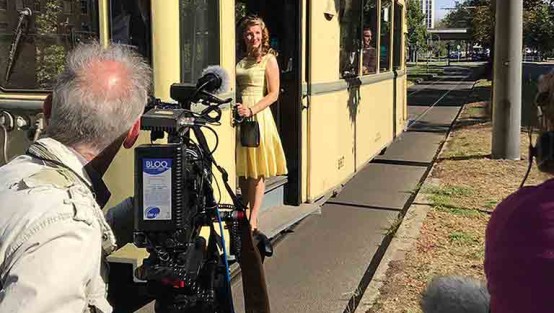 Kameramann filmt die Schauspielerin in der Tür einer historischen Straßenbahn.