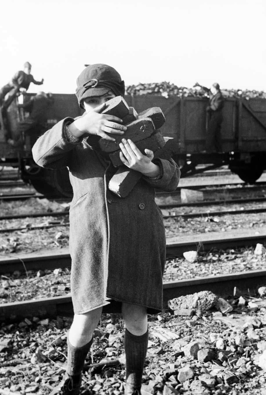 Kind mit Kohlen auf dem Arm vor Güterwaggon