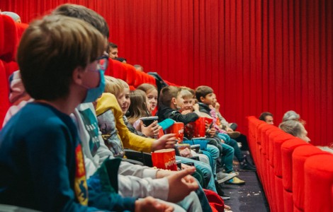 Kinder einer dritten Klasse sitzen im Kinosaal