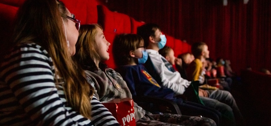 Kinder sitzen im Kinosaal und schauen nach vorne auf die Leinwand