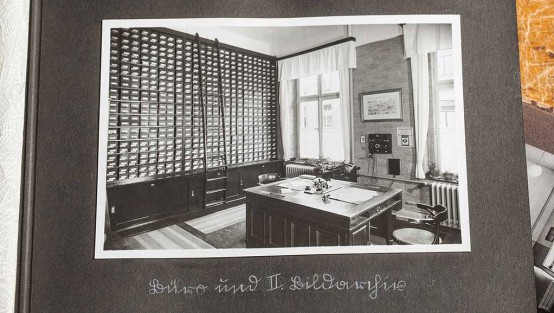 Schwarz-weiss-Foto eines Büros mit einem großen Holzschreibtisch und Regalen bis zur Decke