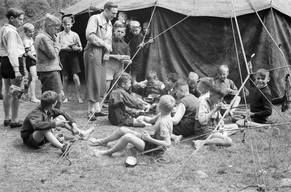 Jungen sitzen vor einem Zelt und essen