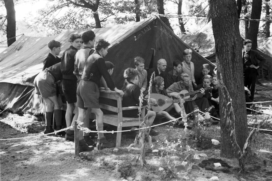 Jungen sitzen vor einem Zelt und musizieren