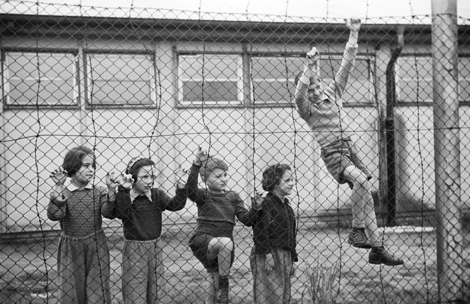 Kinder stehen hinter einem Zaun