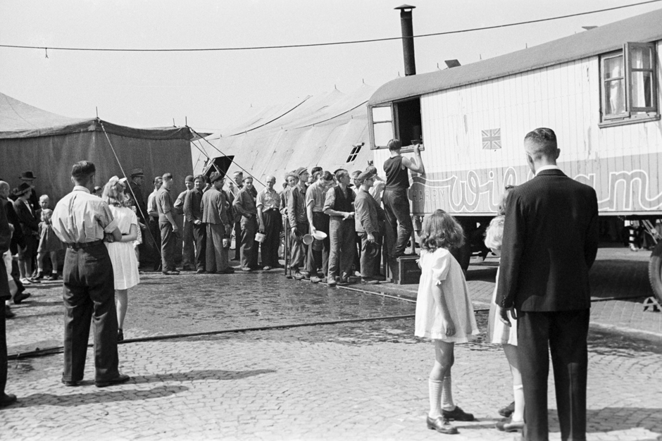 Menschen stehen in einer Schlange vor einem Zirkuswagen