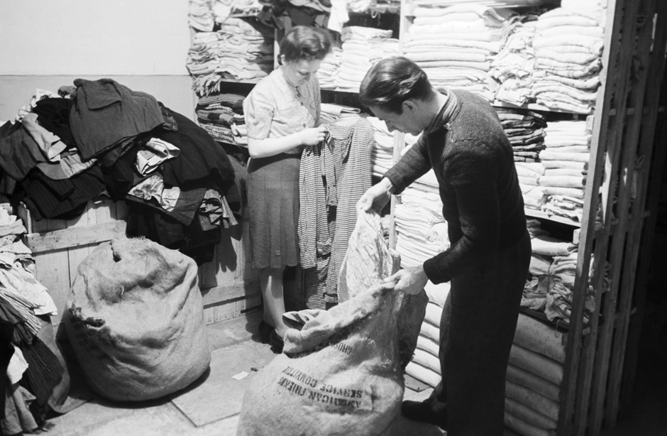 Zwei Personen sortieren Kleiderspenden in einer Kleiderkammer