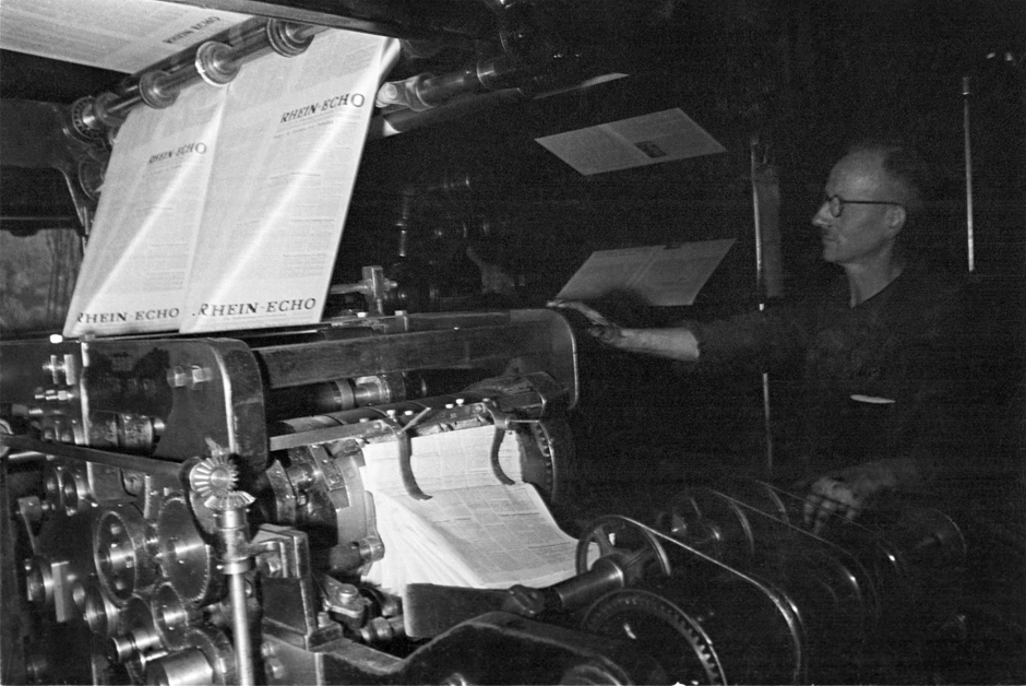 Ein Mann bedient eine Druckmaschine in der Druckerei