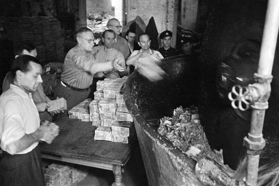 Männer werfen Geldscheine in eine Presse
