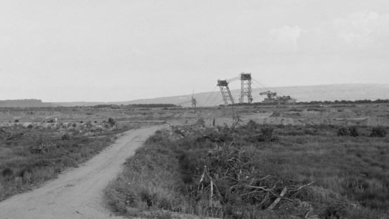 Ein Feldweg mit dem Bagger des Tagebaus im Hintergrund