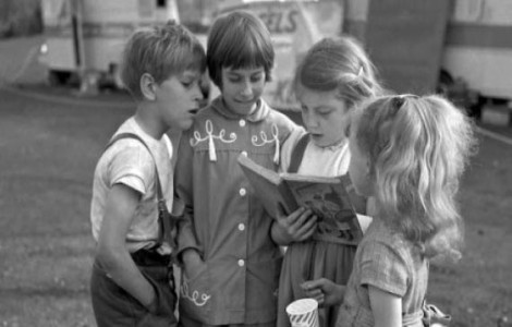Vier Kinder lesen gemeinsam in einem Kinderbuch