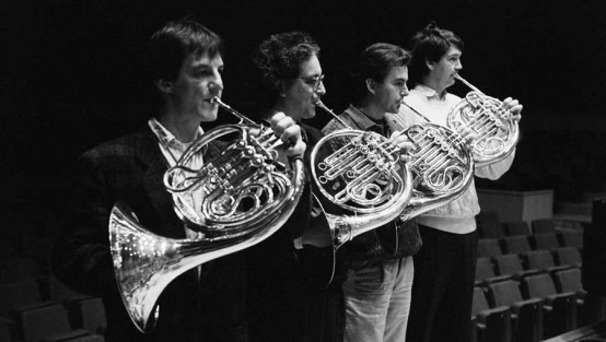 Vier Männer mit Hornblasinstrumenten auf einer Konzerthausbühne
