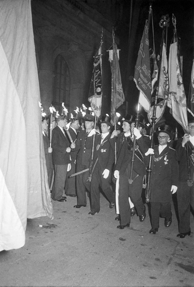 Umzug mit Männern, die Fackeln und Fahnen tragen.