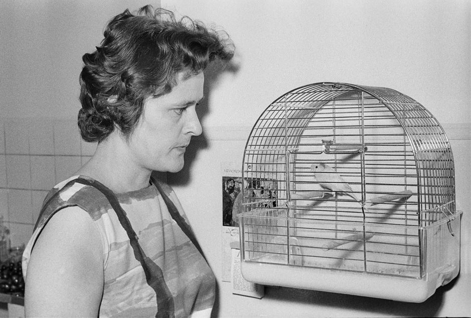 Eine Frau steht neben einem Vogelkäfig.