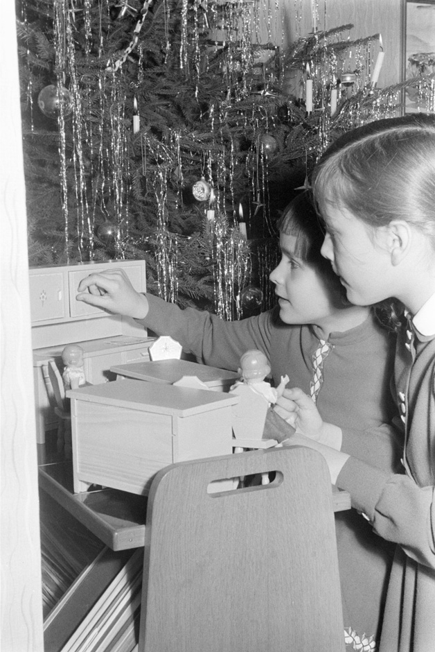 Zwei Mädchen spielen mit Puppenmöbeln.