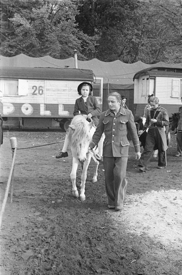 LVR-ZMB, H. Berben Kinder reiten auf Ponys, die von Mitarbeitern des Zirkus geführt werden.