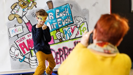 Junge posiert für Fotografin vor Kinderrechte-Wand