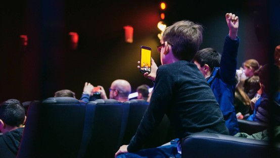 Junge mit Handy im Kinosaal