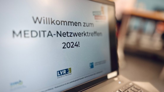 Die Willkommens-Folie zum MEDITA-Netzwerk-Treffen auf einem Laptop im Vordergrund