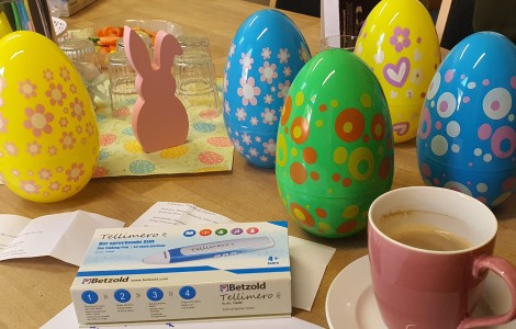 Der sprechende Stift "Tellimero" inmitten von großen bunten Ostereiern aus Plastik, einer Kaffeetasse und einem rosa Dekohasen.