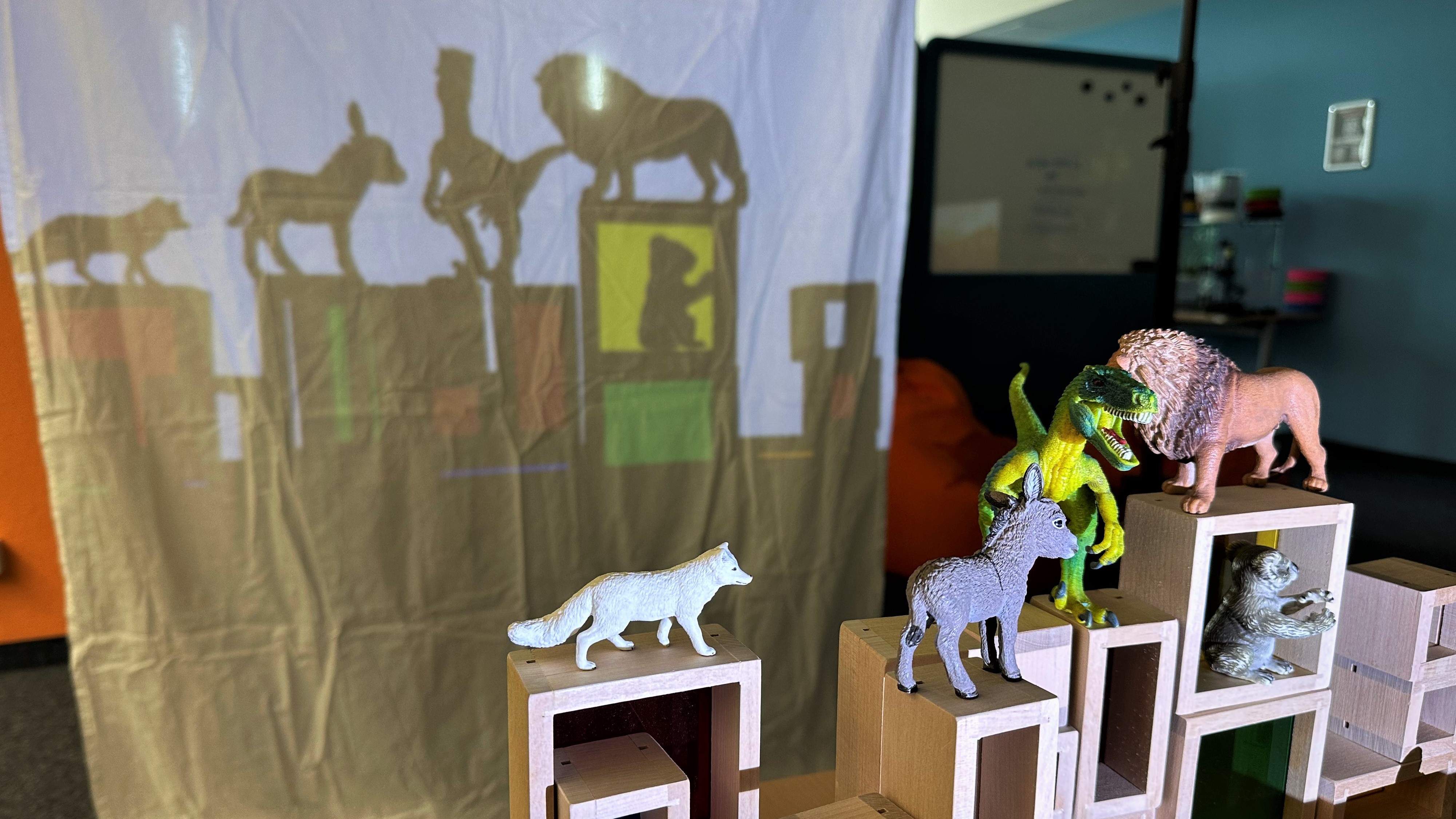 Bunte Fensterbausteine und Tierspielzeuge werfen im weißen Lichtschein schöne und spannende Schatten an die Leinwand.