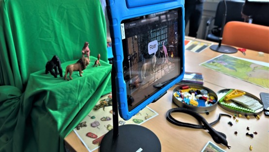 Ein iPad ist auf einem Stativ vor StopMotion-Requisiten aufgebaut, um mittels dem Greenscreen einen Film zu erstellen.