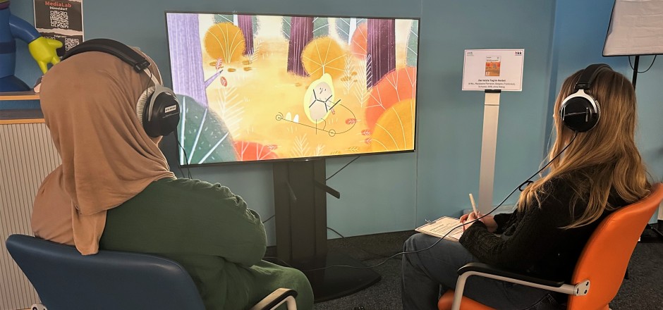 Die Teilnehmenden sichten konzentriert Kurzfilme mit Kopfhörern auf den Ohren.