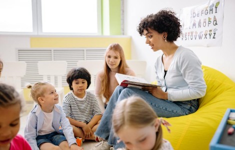 Junge Lehrerin liest Kindern aus einem Buch vor.