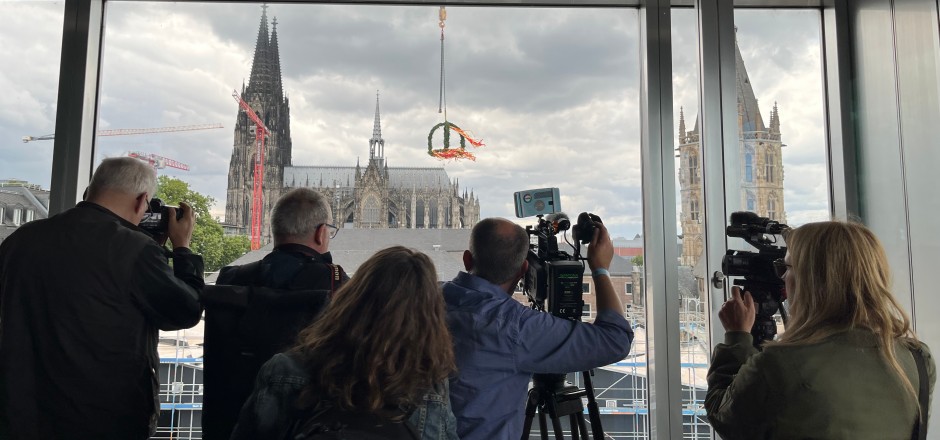 Menschen vor einem Fenster, im Hintergrund der Kölner Dom.