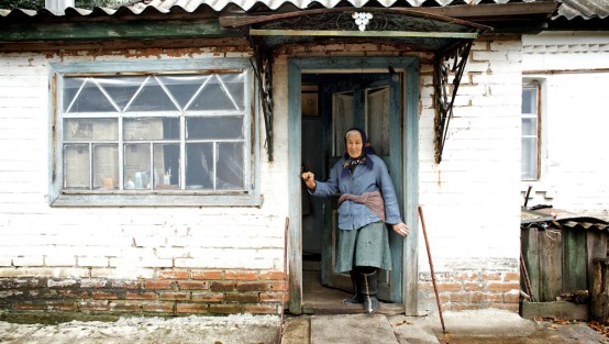 Eine alte Frau steht im Türrahmen ihres Hauseingangs