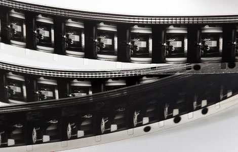 Ein Bild von Filmstreifen, die mehrere Frames eines schwarz-weißen Fotos einer Straßenszene mit Gebäuden und einem Gehweg zeigen.