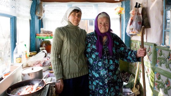 Zwei Frauen mit Kopftüchern in einer ganz einfach ausgestatteten Küche
