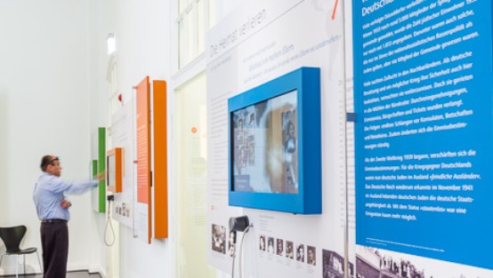 Besucher in der Ausstellung, schaut sich Touchscreen an.