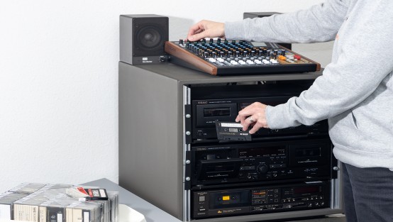 Eine Person legt Audiokassette in Digitalisierungsmaschine ein.