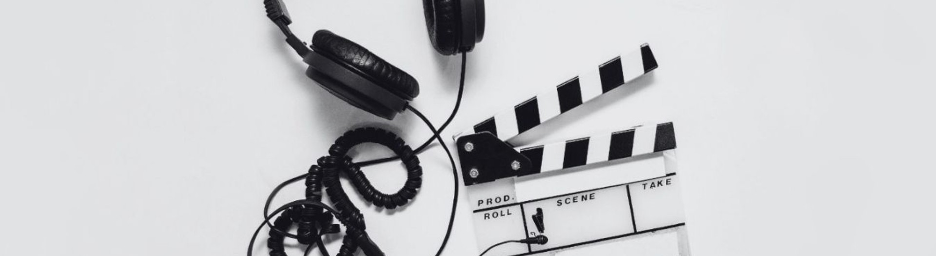 Kopfhörer, Filmklappe und Mikrofon vor weißem Hintergrund