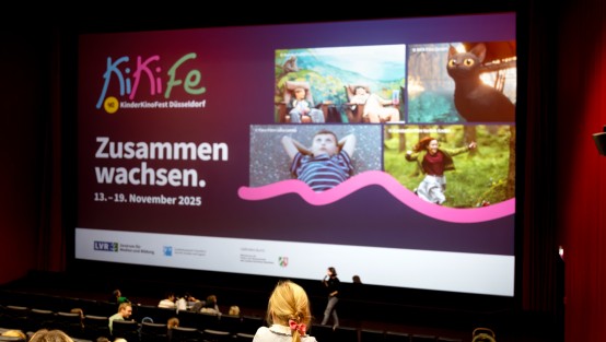 Kinder im Kinosaal vor einer bunten Leinwand